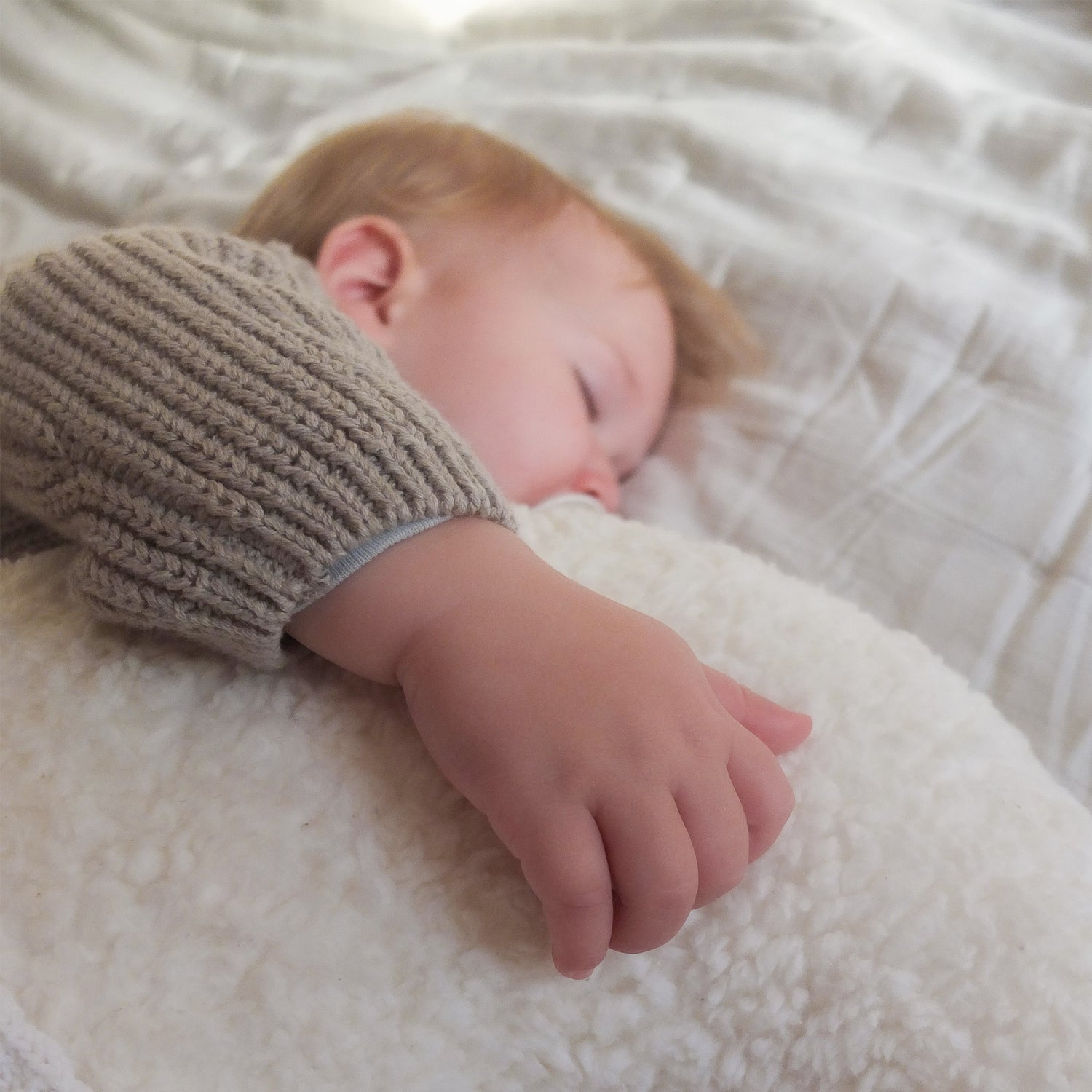 Niedliches Baby schläft friedlich an das Kotenkram Mondkissen aus Teddyplüsch aus 100 % Baumwolle in cremeweiß mit Personalisierung gekuschelt