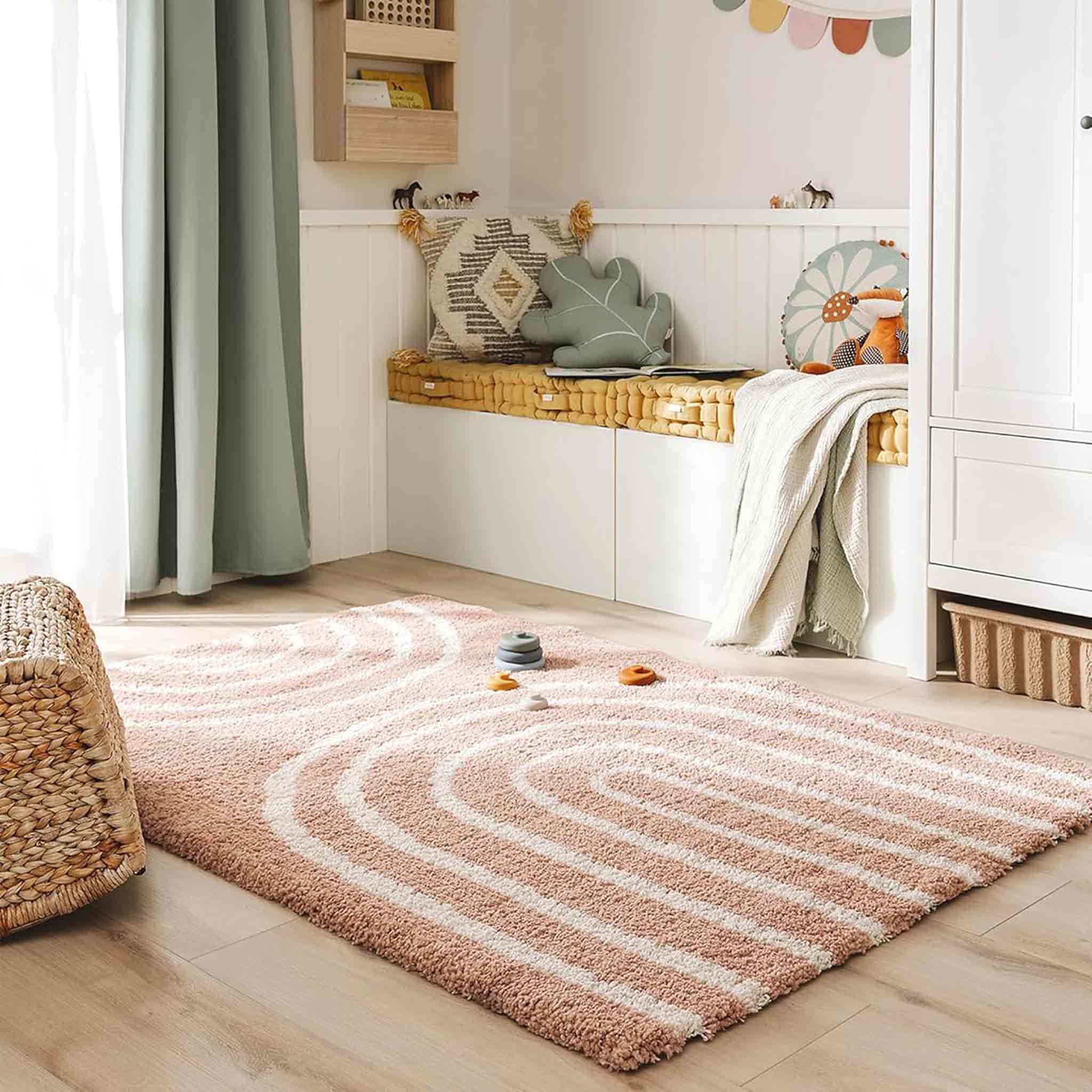 Wundervoll weicher und üflegeleichter Kinderteppich von benuta. Rosa mit cremeweißen grafischen Regenbögen ist der Teppich modern und verspielt