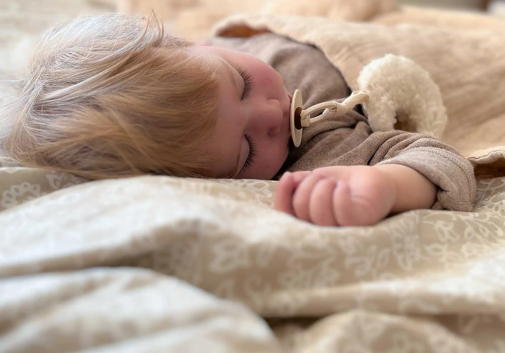 Schlafendes Baby mit handgefertigtem Schnulleranhänger in Mondform von Kotenkram – liebevolle Babydeko im natürlichen Stil